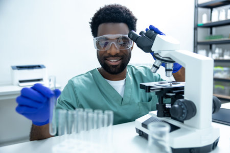 Male scientist looking under microscope and using test tubesの写真素材