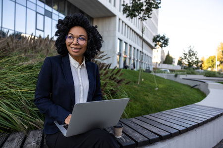 Manager sitting in the park and working on laptopの写真素材