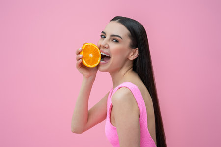 Happy young woman with orange in hands looking enjoyedの写真素材