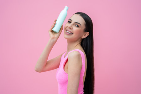 Pretty young woman in with a bottle of shampoo in handsの写真素材