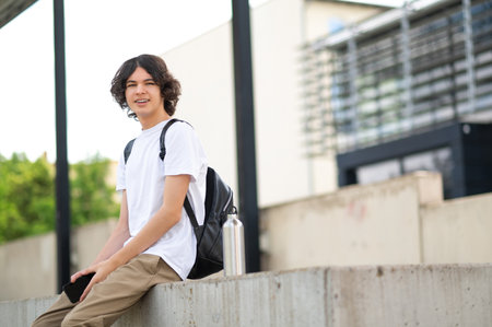 Dark-haired teenager sitting on the blocks and resting after classesの写真素材