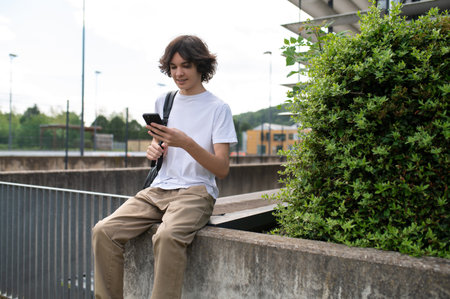 Young guy in white tshirt with a phone in hands looking contentedの写真素材