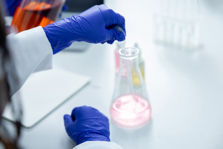 Unrecognizable researcher holding reagent tube and analyzing fluid samples in laboratory