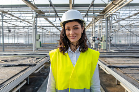 Smiling young female engineer in a hardhat and yellow vestの写真素材