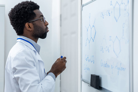 Male teacher writing something on a blackboard on a chemistry lesson