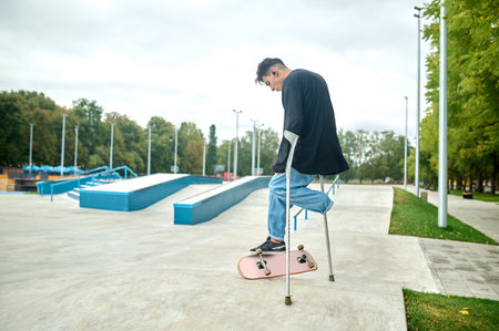 Young guy on crutches making efforts to jump