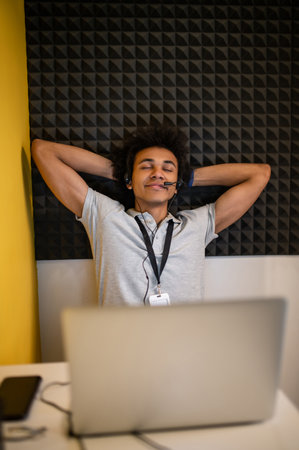 Young curly-haired man stretching and feeling tired after a long work