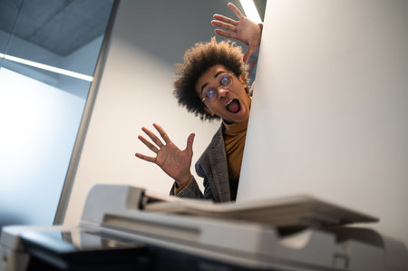 Waist up of a astonished young man near the xerox machineの写真素材