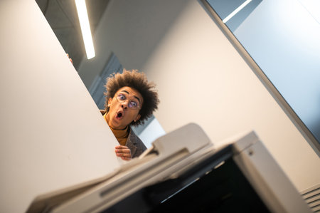 Waist up of a astonished young man near the xerox machineの写真素材