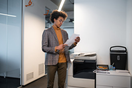 Young man putting the documents in the file and looking involvedの写真素材