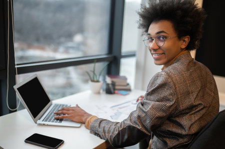 Young smiling man sitting a the laptop and looking contentedの写真素材