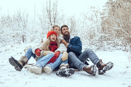 Cute young family having fun in a winter forest and looking enjoyedの写真素材