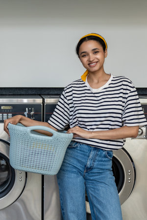 Woman in laundromat using commercial washer to clean dirty clothesの写真素材
