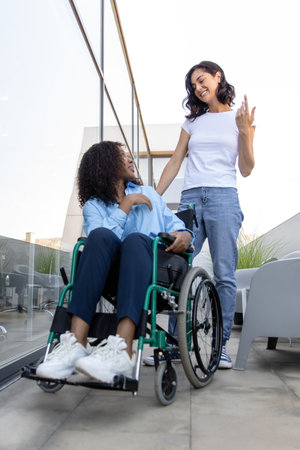 Young woman carrying a wheelchair with a disabled african american womanの写真素材