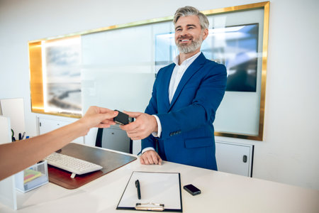 Businessperson handing keys to client after closing successful deal in showroom