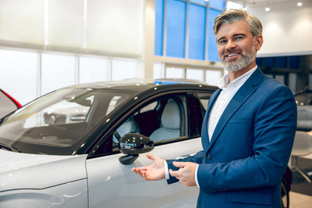 Professional salesman presenting new car in dealership showroomの写真素材