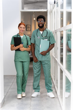 Female medic standing with African American male colleague in hospital hallの写真素材