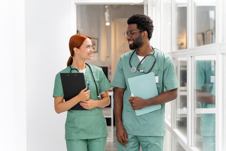 Hospital staff engaged in professional discussion while walking in medical hallの写真素材