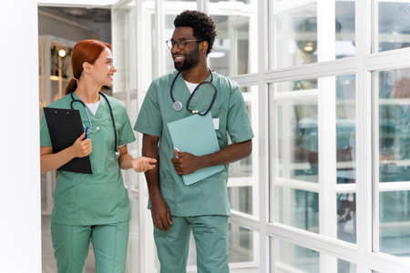 Male and female doctors in healthcare office discussing diagnosis and treatment in hospital hallの写真素材