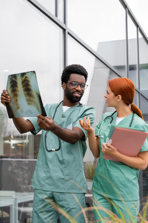 Man doctor talking with woman nurse in medical center analyzing patient diagnosis and examining x ray pictureの写真素材