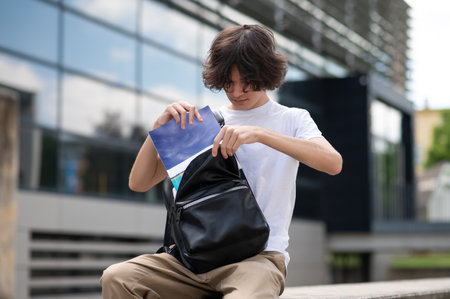 Smart guy putting book into backpack in town embracing summer learning lifestyleの写真素材