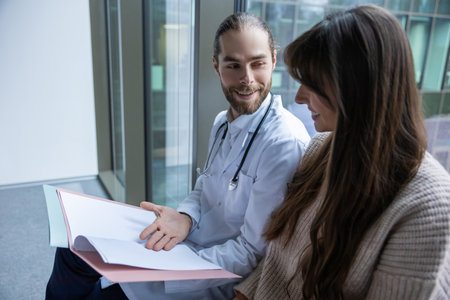 Male specialist holding file and documents discussing treatment with woman patient