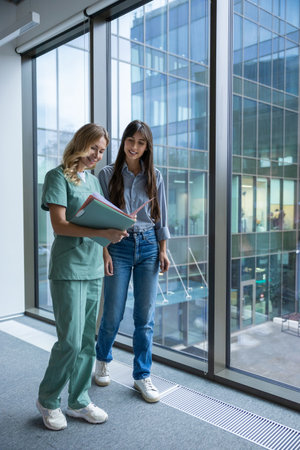 Female doctor in hospital clinic wearing medical uniform reviewing papers with patientの写真素材
