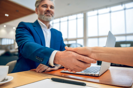 Man with customer in car dealership together and handshakingの写真素材