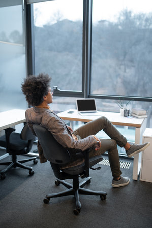 Man wearing suit sitting in office with big windowの写真素材
