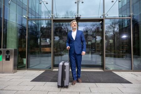 Mature businessman with a big suitcase arriving to destinationの写真素材