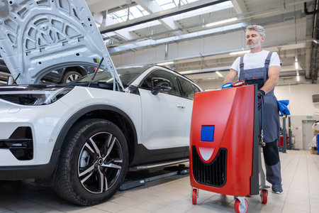 Bearded man technician checking car air conditioning system refrigerant rechargeの写真素材