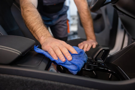 Worker using rag to wipe down dirty transport in garage after repair workの写真素材