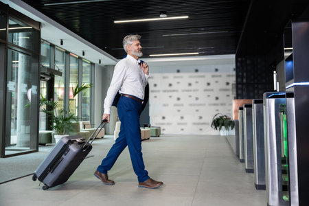 Bearded business tourist with luggage walking to security gatesの写真素材