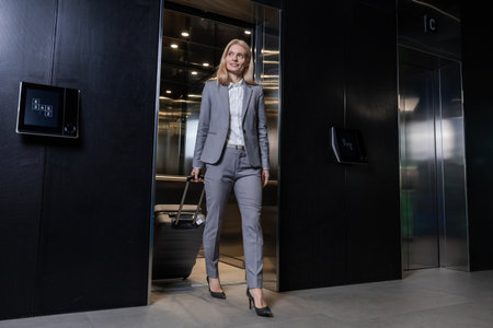 Blonde woman in elegant suit going out of the elevator in business centerの写真素材