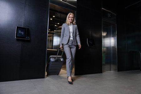 Blonde woman in elegant suit going out of the elevator in business centerの写真素材
