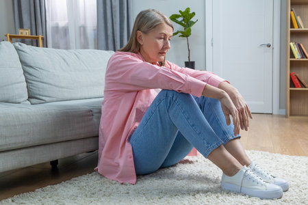 Aging woman in pink shirt feeling emotionally stressed and frustratedの写真素材