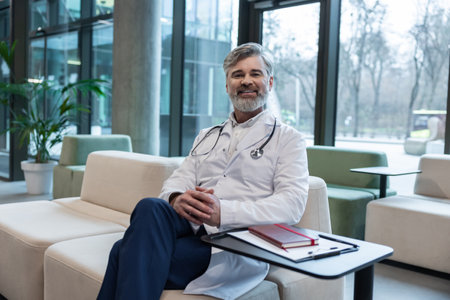 Smiling mature male doctor in lab coat looking positive and contentedの写真素材