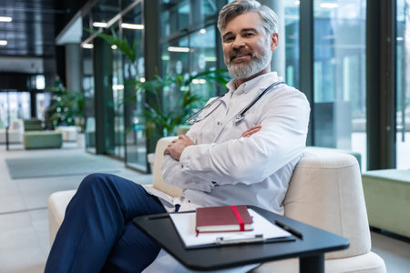 Smiling mature male doctor in lab coat looking positive and contentedの写真素材