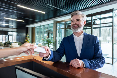 Bearded male staff at reception counter giving key cardの写真素材