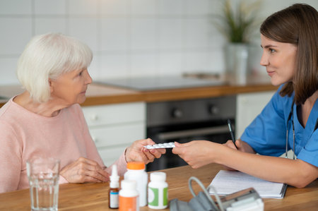 Female doctor providing care and medicine to elderly patient giving assistance with treatmentの写真素材