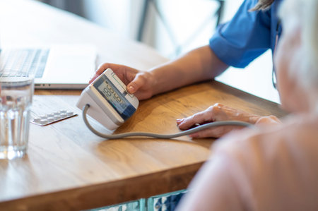 Nurse assisting senior patient with heart exam taking pressure measurementの写真素材