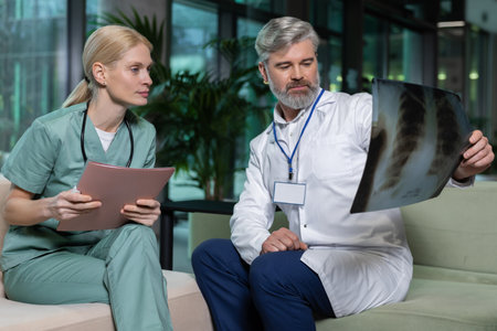 Two doctors sitting next to each other and discussing xray resultsの写真素材