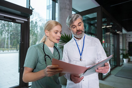 Female and male doctors discussing patients medical case and looking excitedの写真素材