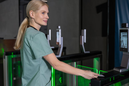 Female doctor in lab coat passing through security control by using access cardの写真素材