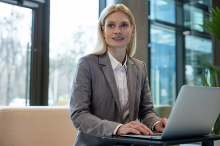 Female entrepreneur sitting on sofa working on laptop in officeの写真素材