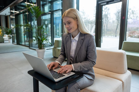 Caucasian woman manager typing on notebook while sitting in officeの写真素材