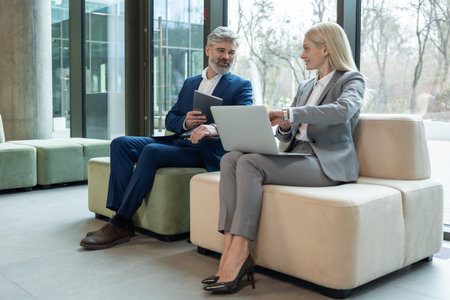 Businessman and woman manager sitting on sofa in office discussing corporate ideasの写真素材