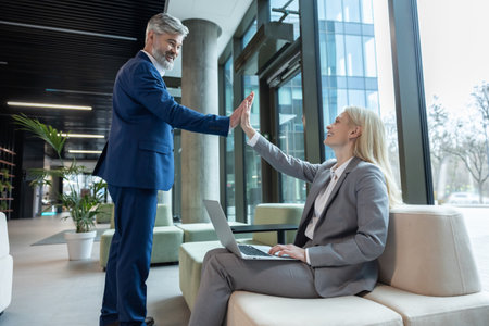 Business partners making successful profitable deal smiling and giving each other high fiveの写真素材