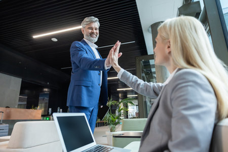 Entrepreneur and coworker in office discussing online business contract giving high fiveの写真素材
