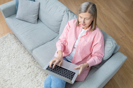 Top view of a woman sitting on the sofa with a laptopの写真素材
